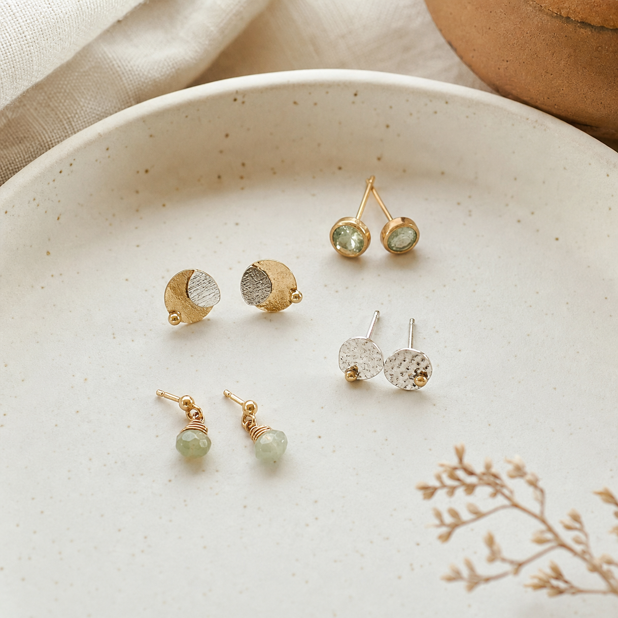 Small handmade earrings arranged on an ivory tray.