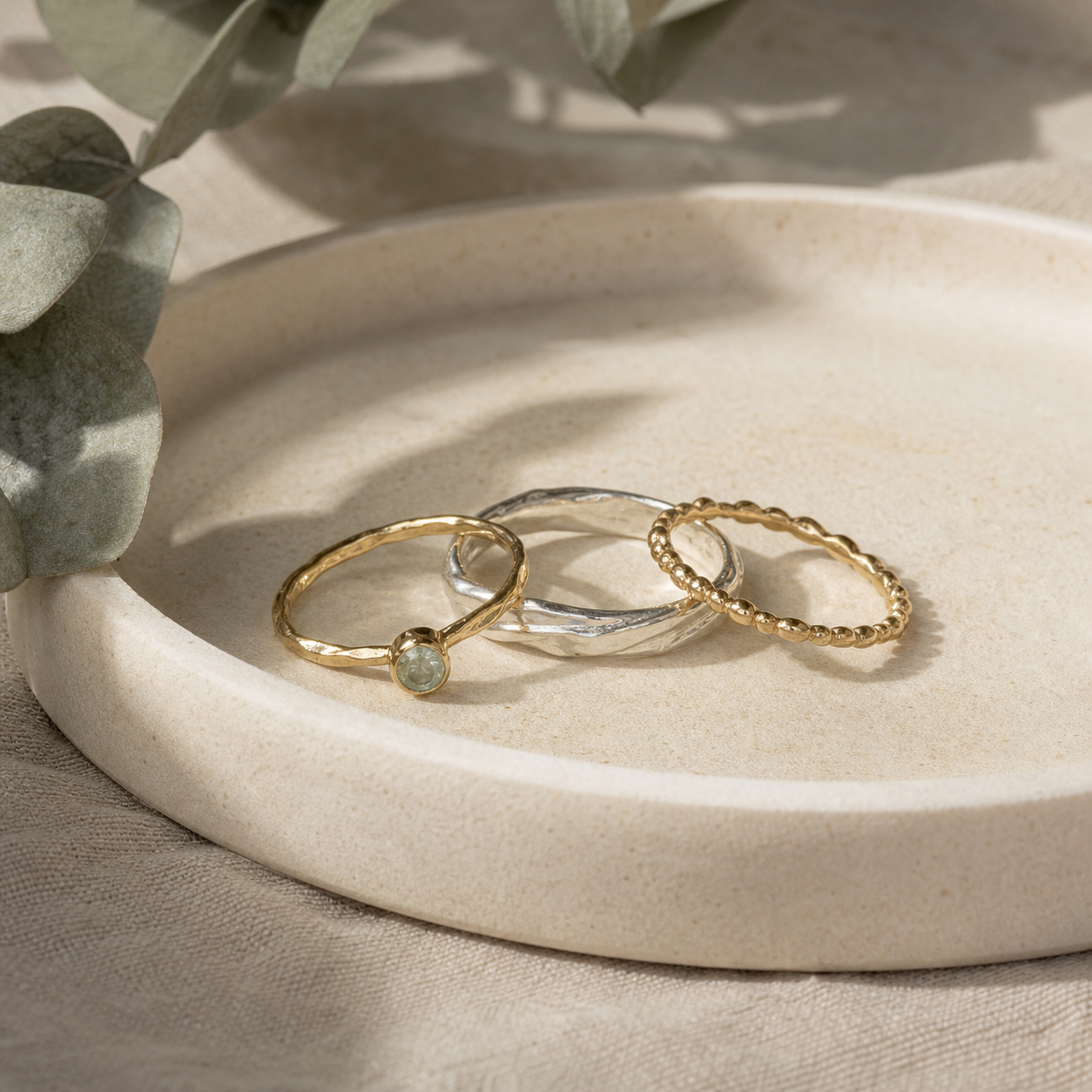 Handmade mixed-metal rings on a ceramic tray.